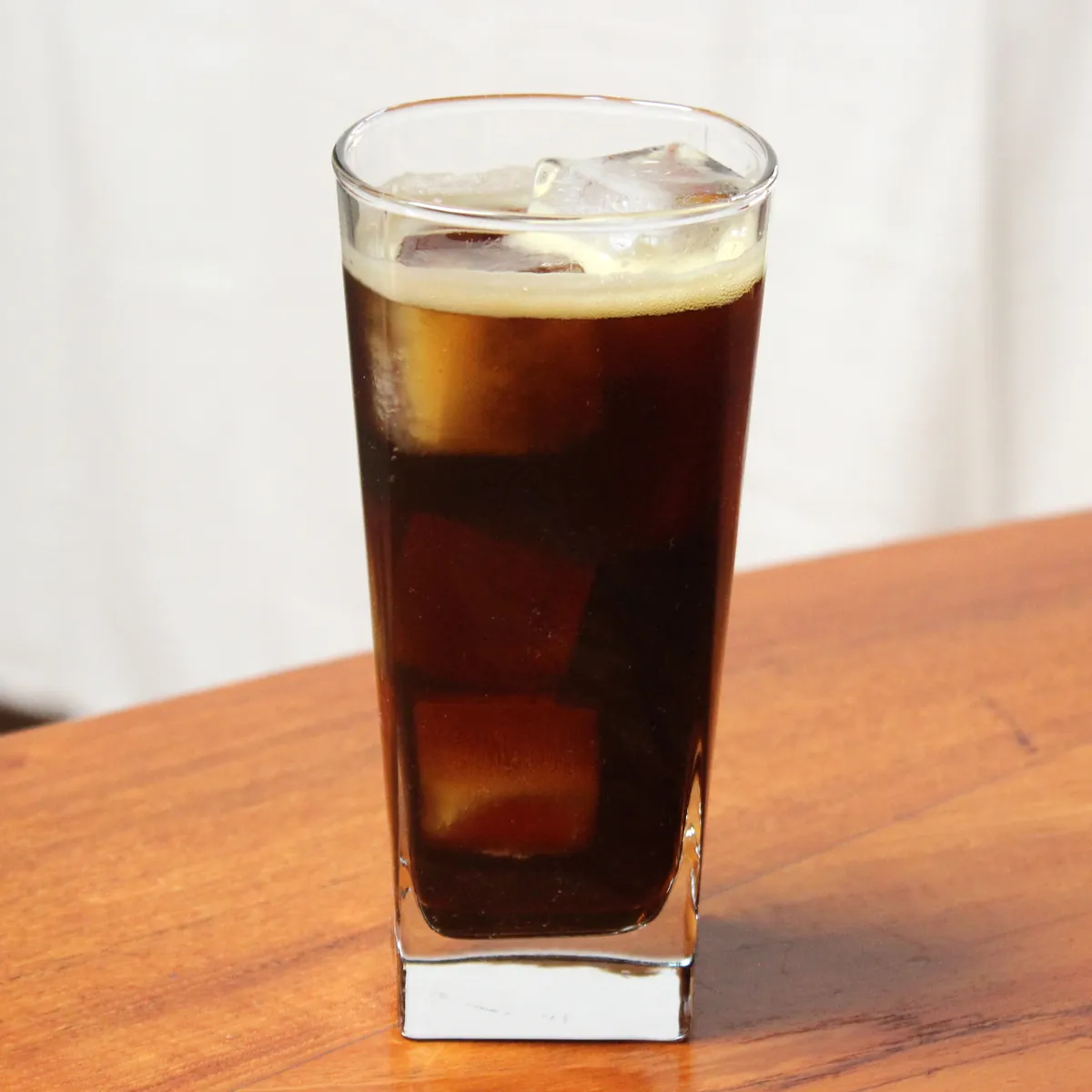 氷とともにグラスに注がれた褐色の飲み物の写真