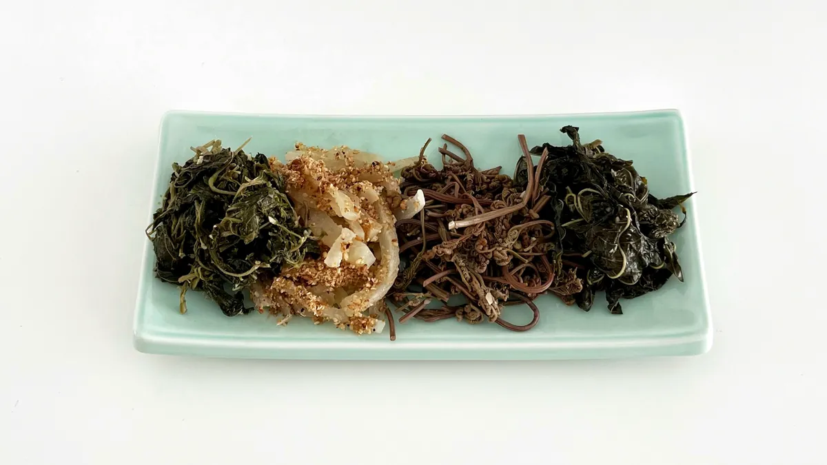 水色の角皿に、種類の異なる茶色や緑色の干しナムルが4種類並んでいる