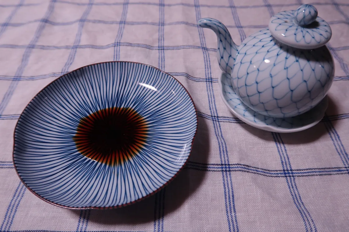 醤油差しから白い小皿（手塩皿）へ細く注がれる濃い褐色の濃口醤油