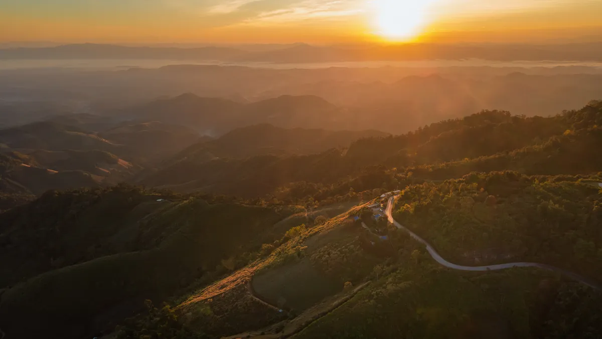 夕日に照らされた幾重にも連なる山並みと、麓を通る一本道