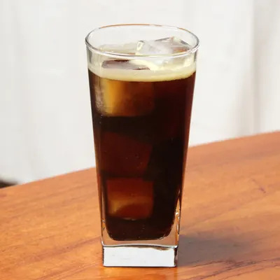 氷とともにグラスに注がれた褐色の飲み物の写真
