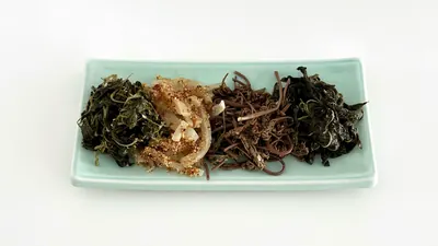 水色の角皿に、種類の異なる茶色や緑色の干しナムルが4種類並んでいる