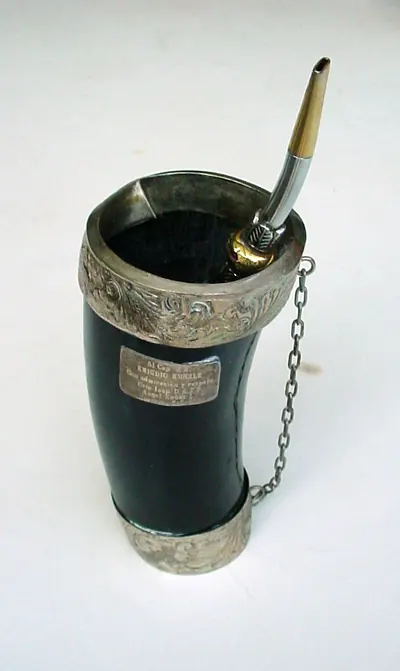 銀の装飾が施された黒い角製の器に、金属製の吸い管が差し込まれている