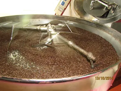鍋状の器具でコーヒー豆を炒っている様子の写真