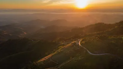 夕日に照らされた幾重にも連なる山並みと、麓を通る一本道